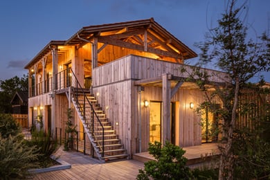 Maison à bardage bois vertical et terrasses en bois au crépuscule, en bord de mer à Contis (Landes)