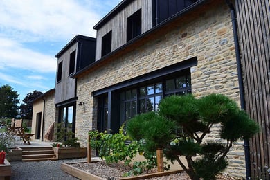 Maison en pierre rénovée à La Baule, façade en pierre et bardage bois avec grandes baies vitrées