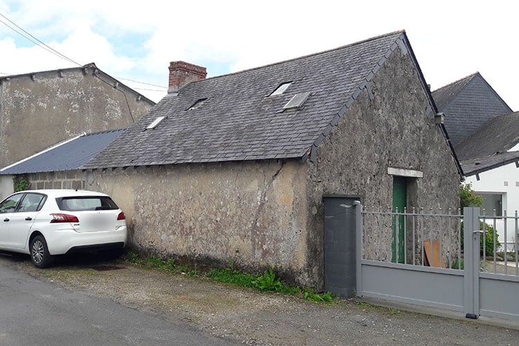 Dépendance basse en pierre à Saint-Nazaire avant travaux, façade sur rue et pignon couverts d'un enduit ciment gris fissuré